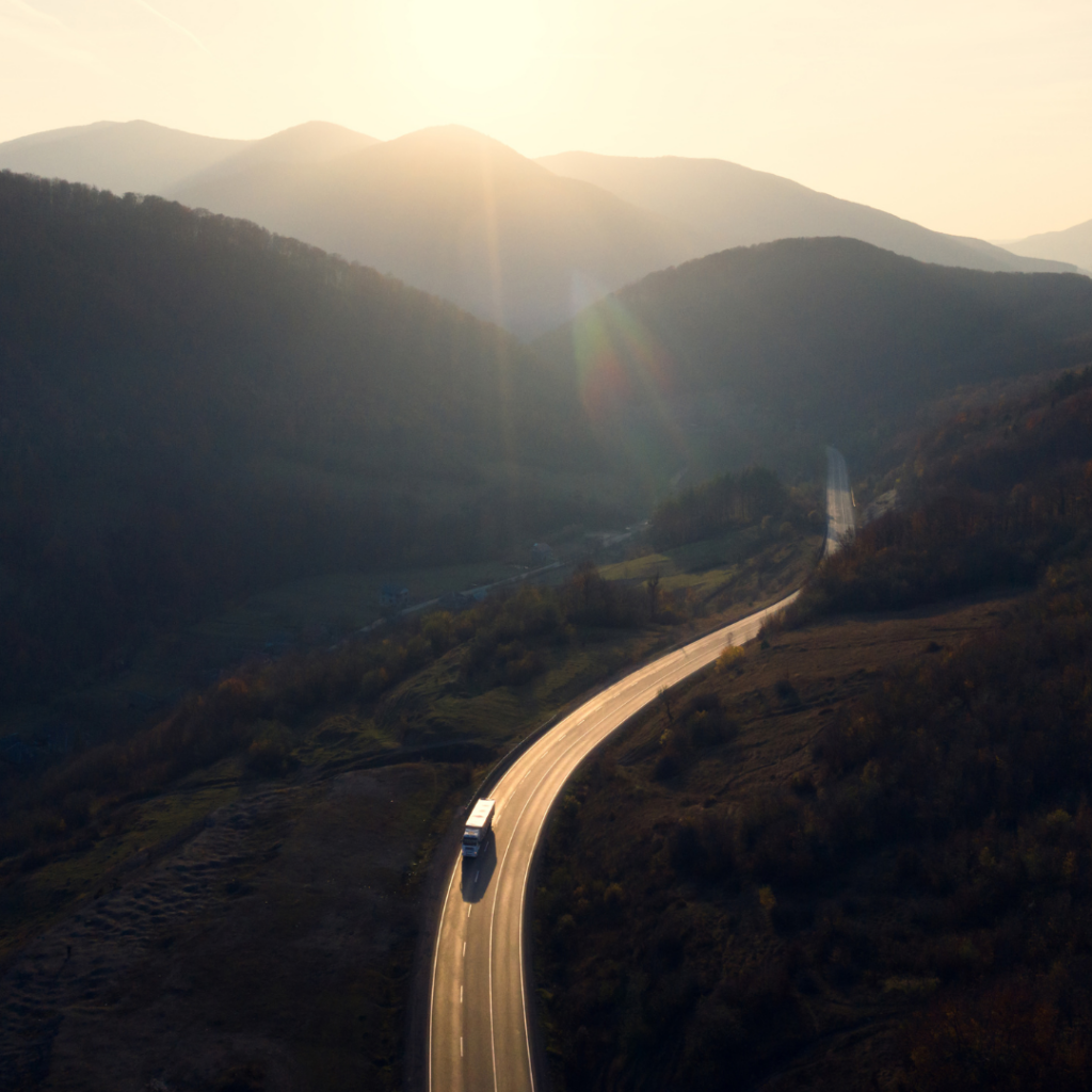 Carretera de montaña con un camión al amanecer